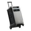 A studio product photo of the Anker SOLIX F3800 Plus whole home backup power station on a white background, showing its silver-grey contoured chassis, built-in wheels, extended telescoping handle, and active front LCD display.