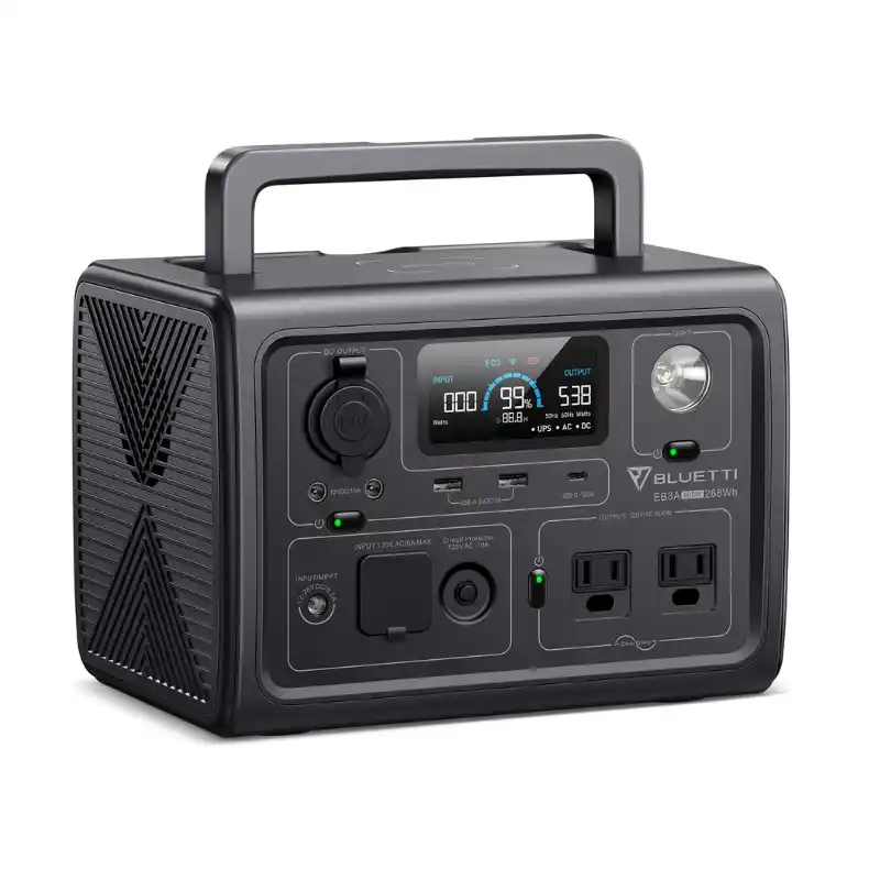 A front-angled studio product photo of the compact BLUETTI EB3A portable power station, US version, against a white background. The unit features a dark charcoal grey body, a centred LCD display showing 99% battery, two US AC outlets, and a built-in LED flashlight.