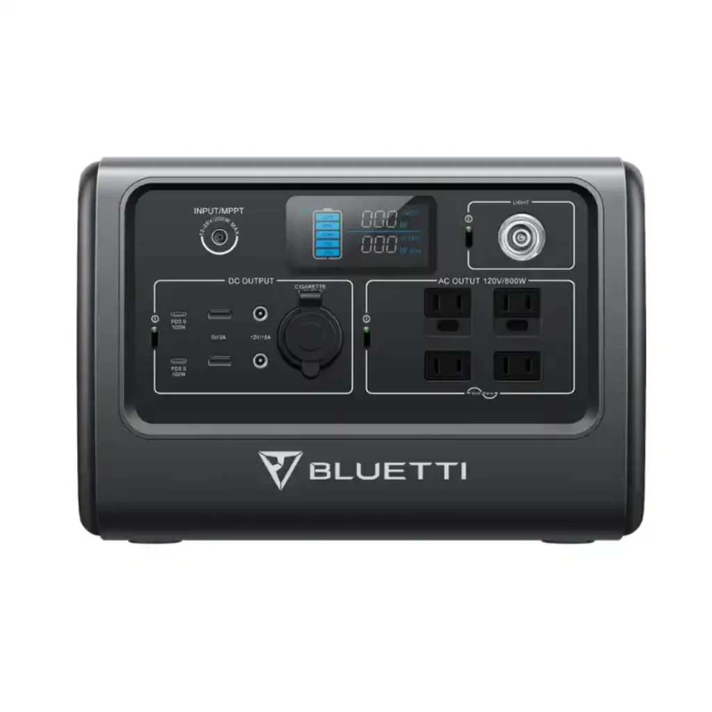 A symmetrical front-facing studio product photo of the BLUETTI EB70S portable power station on a white background, displaying its compact dark grey body, centered LCD display, built-in LED light, and covered DC, USB, and AC outlets.