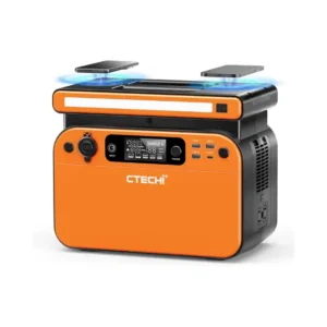 A studio product photo of the CTECHi GT500 portable power station against a white background, featuring an orange-and-black chassis, a warm-white front LED light bar, and two smartphones positioned above the integrated wireless charging pads on top.