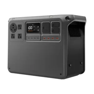 A studio product image of the DJI Power 2000 portable power station, showing its compact dark gray body, integrated corner carry handles, LCD screen displaying 100% battery capacity, four USB-C ports, four USB-A ports, four AC outlets including a NEMA TT-30 RV port, and dual SDC drone charging ports.